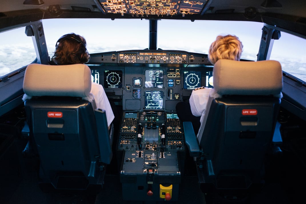 Pilot And Co-Pilot Sitting In Flight Simulator Cockpit